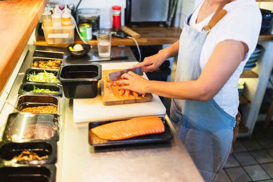 Business Owner cutting salmon Behind Counter in Restaurant