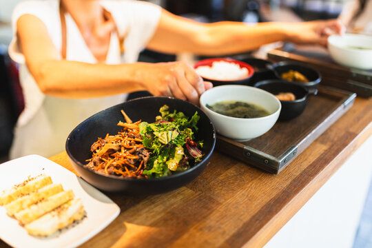 Korean Chef Finalizing Plates for Service Behind Counter