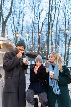 Family eat donuts and drink hot tea in a food court outdoors