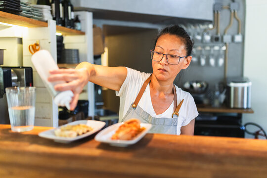 Korean Chef Finalizing Plates for Service Behind Counter