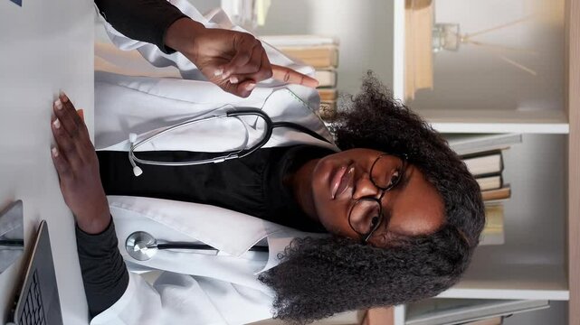 Vertical video. Doctor rejection. Refusing warning. Healthcare medical specialist woman in white clinic uniform with stop gesture prohibition hand sign at hospital workplace desk.