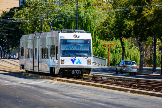 VTA light rail train travels along San Carlos Street in downtown San Jose surrounded by green trees and urban scenery - San Jose, California, USA - September 15, 2024