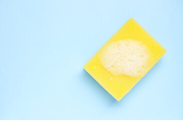 Yellow cleaning sponge with foam  on light blue background. 