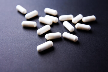 Creatine capsules on dark paper background. Soft focus. Copy space.	
