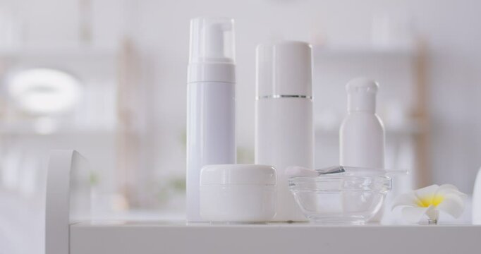 White bottles, cream jars and cosmetic skin care products for female skin and body care in empty beauty spa salon room. Spa treatment, wellness and cosmetology concept. 4k video. Slow motion video.