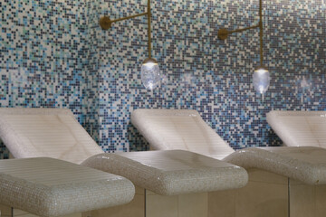 Thermal suite with heated loungers in mosaic tile design or relaxation chairs in spa or wellness...
