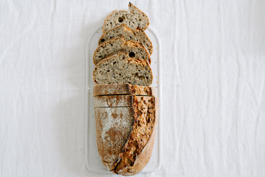 Partially sliced seeded bread loaf on a white platter