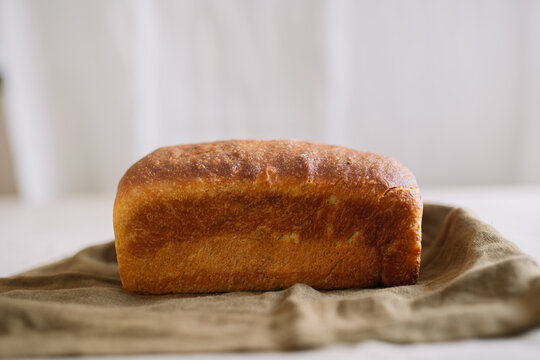 Golden-brown loaf of bread resting on olive cloth