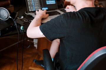 A man working in home studio while wearing health monitoring device 