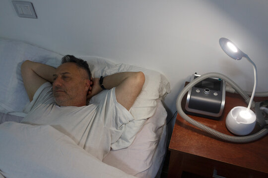 Man Relaxing in Bed with CPAP Machine for Sleep Apne
