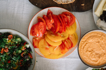 Colorful slices of tomatoes with mixed salad and dip