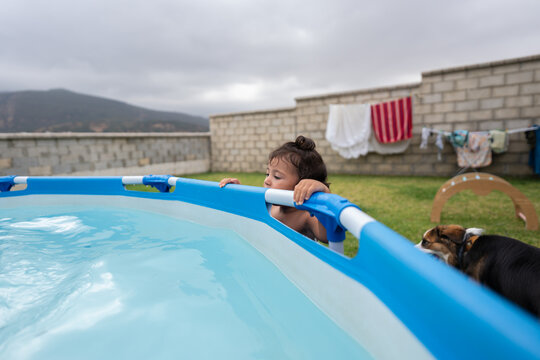 Curious little girl looking at the water in an inflatable pool