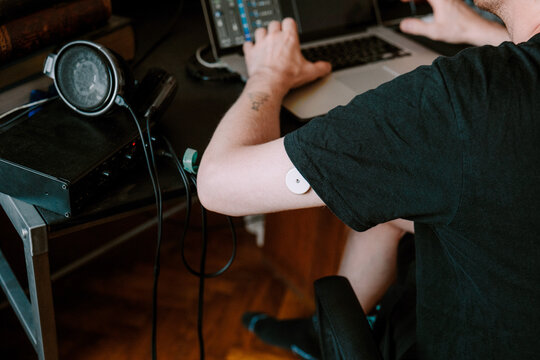 A man working in home studio while wearing health monitoring device 