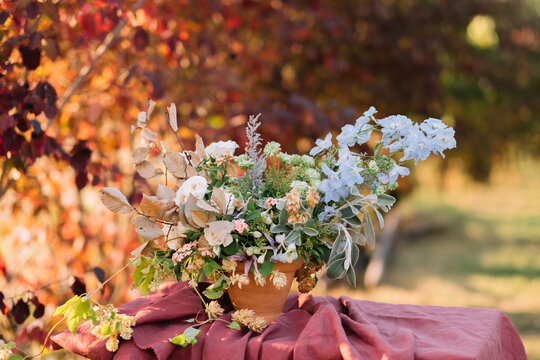 Autumn-hued floral bouquet in rustic pot on table.