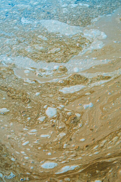 Brown, floating foam on surface of tide pool water