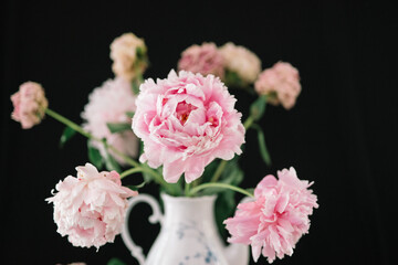 Close-up of pink flowers in vase with dark backdrop.