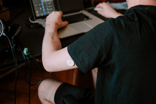 A man working in home studio while wearing health monitoring device 