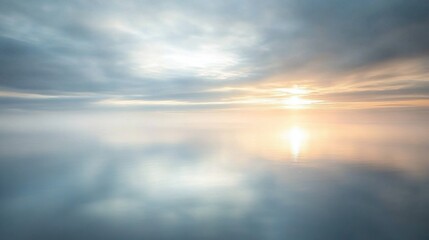 Obraz premium Calm sea with a light mist drifting over the water, under the soft glow of an overcast sky.