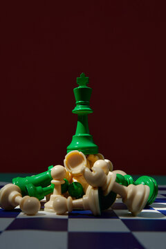 green king surrounded with beige chess pieces on chess board