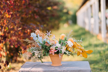 Elegant floral arrangement on cloth-covered table outdoors.