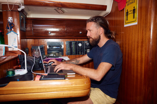 Man works on a laptop in boat's cabin