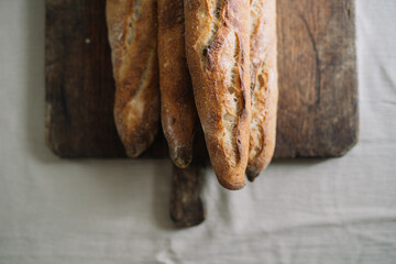 Three fresh baguettes resting vertically on the board.