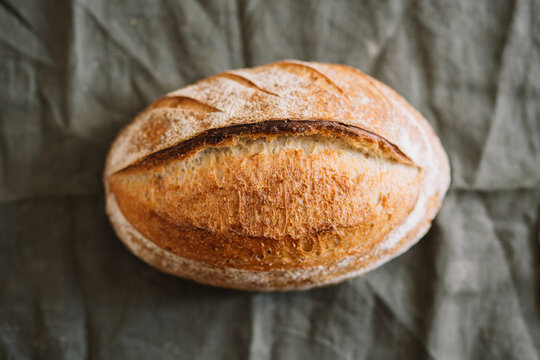 Close-up of a single rustic bread loaf on green cloth