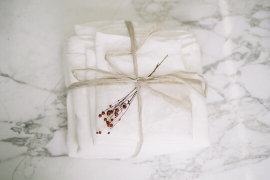 Neatly tied white linens with string and red berries sprig.