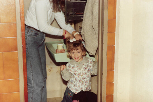 Mother arranging the hair of her daughter at home