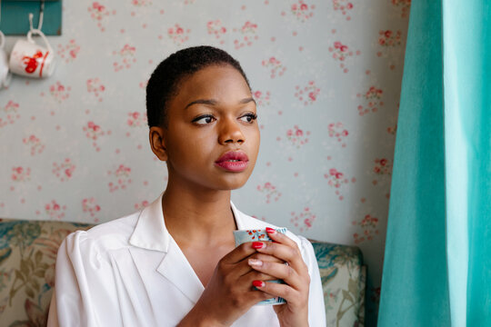 Thoughtful  Black woman holding a cup indoors