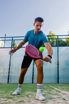 A university paddle tennis athlete striking a ball with a racket