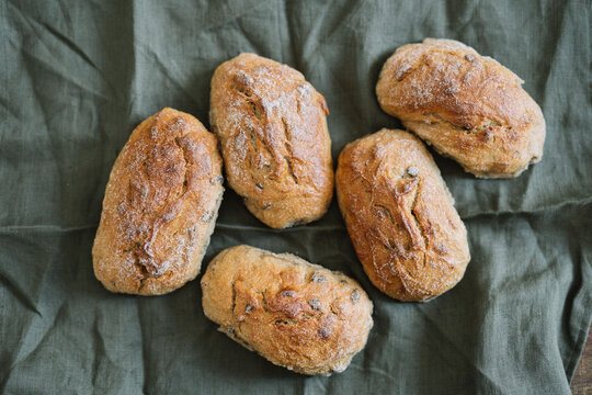 Five rustic bread rolls placed on green cloth backdrop
