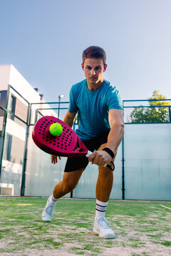 Padel player hitting a ball on a court inside college sports facility