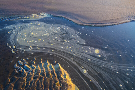 Tide pool of swirling, foamy water at dusk