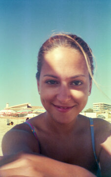 ugc selfie with analog film camera of a young woman on the beach