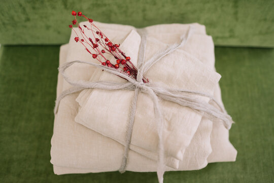 Natural linens tied with string and red sprig on green.