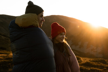 Couple  with sleeping bag  in mountains background.