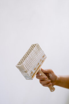Hand holding paintbrush diagonally with paint on it
