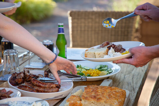 Al fresco family dinner table with barbecued meat and salads. 