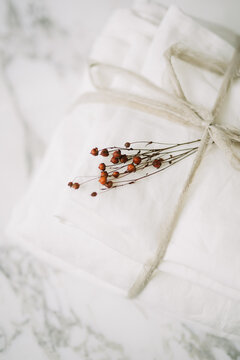 Close-up of white linens tied with string and red berries.