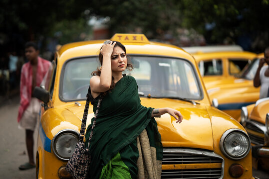 Good looking Indian woman standing in a street with background of taxi