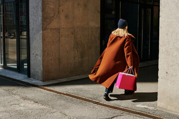 Woman walking with a pink shopping bag along a city street