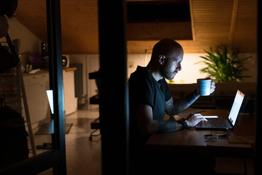 Man working from home late at night with laptop and coffee