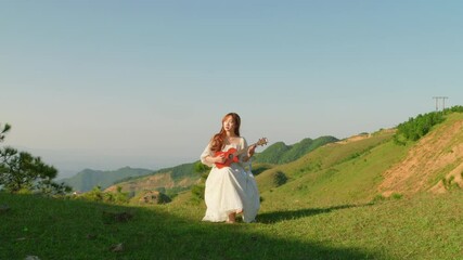 woman sit in nature play a song with ukulele wearing long white dress