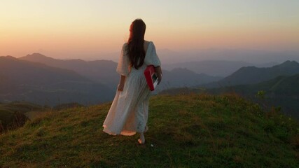 female artist musician walking barefoot in mountains path at sunset wearing elegant long white dress carrying piano keyboard musical instrument