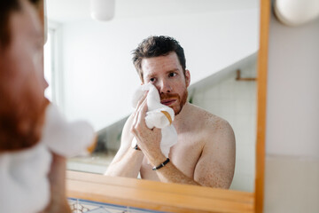 Man uses a hand towel to gently dry the skin of his face