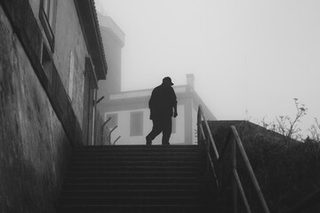 Mysterious figure walking up stairs in foggy urban setting