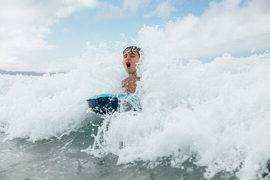 Boy riding waves on a boogie board with water splashing around him