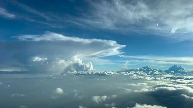 A stormy sky seen from above the sky. A pilot&rsquo;s POV from a jet cockpit flying at cruise level across a blue sky with some golden clouds and a massive cumulonimbus storm cloud ahead. Golden hour