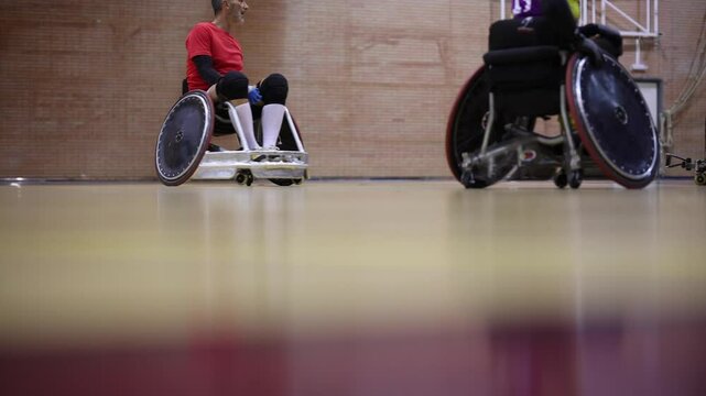 Three wheelchair rugby athletes are moving down the court during a game